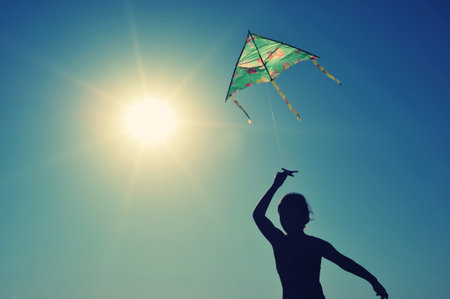 Girl running and flying a kiteの写真素材