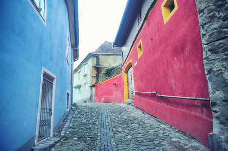 Small street paved and a house with blue and pink walls in the city of Sighisoara, Romania, Transylvaniaの写真素材