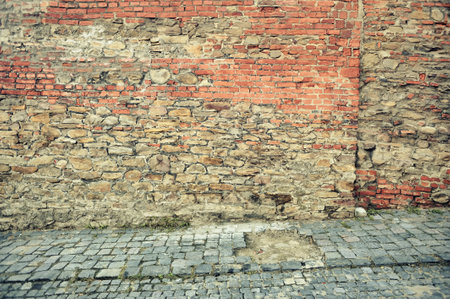 Old red brick wall on a paved street of the cityの写真素材