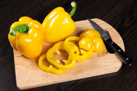 yellow sliced ââpepper on a wooden board on a dark backgroundの写真素材