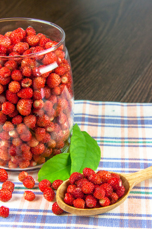 juicy strawberries in a clear jar on a napkin and a wooden spoonの写真素材