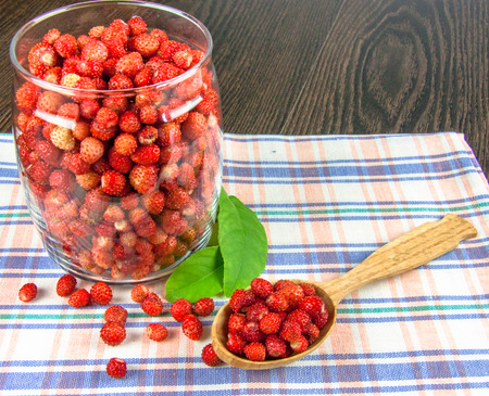 juicy strawberries in a clear jar on a napkin and a wooden spoonの写真素材
