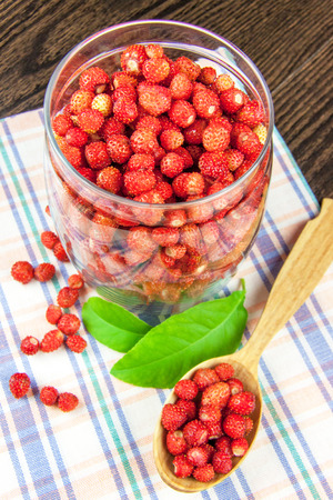 juicy strawberries in a clear jar on a napkin and a wooden spoonの写真素材