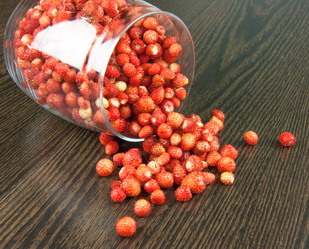 juicy strawberries in a clear jar on wooden tableの写真素材