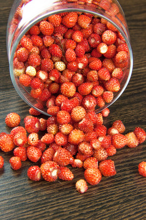 juicy strawberries in a clear jar on wooden tableの写真素材