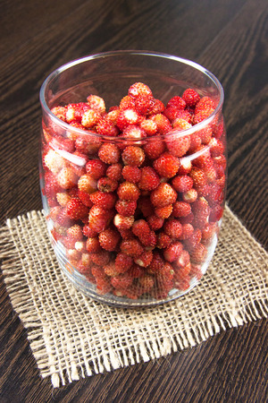 juicy strawberries in a clear jar on wooden tableの写真素材