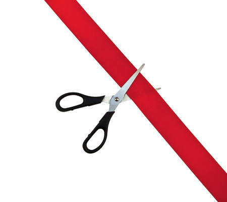 Black scissors cut the red ribbon isolated on white backgroundの写真素材