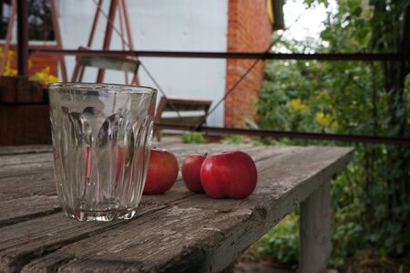 Glass and three apples on a wooden tableの写真素材