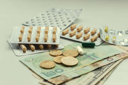 Various tablets are spread out on a table next to paper money of different countries and coins