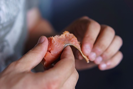 Male hands holding a piece of red smoked fish