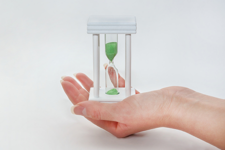 Female hand holds hourglass on white background