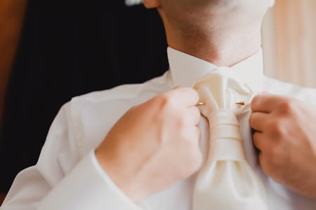 The groom tying his tie, close-upの写真素材