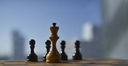 old chess pieces on a chessboard against a blue skyの写真素材