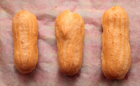 Long rows Eclair shells. Eclairs candy paper. The process of making cakes.