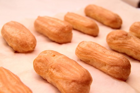 Long rows Eclair shells. Eclairs candy paper. The process of making cakes.