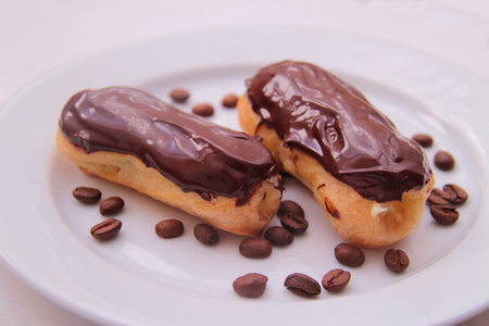 Chocolate eclairs on plate on white background.