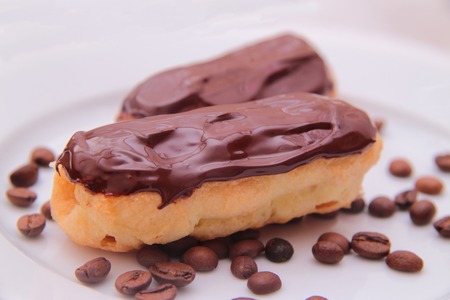 Chocolate eclairs on plate on white background.