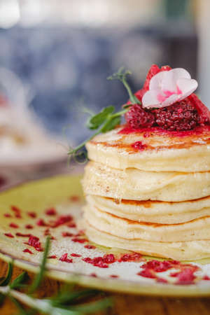 delicious pancakes with syrup in a stack and flower decoration on top a wooden table.の写真素材
