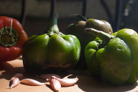 Green pepper and red bell pepper with garlic on the wooden table.の写真素材