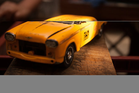 Yellow toy car on a wooden table in a cafe. Selective focus