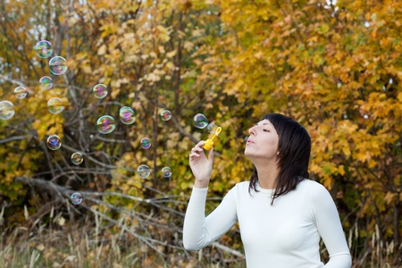 The girl starts up soap bubbles against yellow autumn foliage.の写真素材