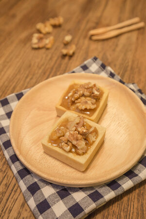Fresh delicious caramel nut tart dessert presented nicely on wooden plate.の写真素材