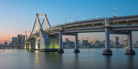 Rainbow bridge at night with Tokyo tower in backgroundの写真素材