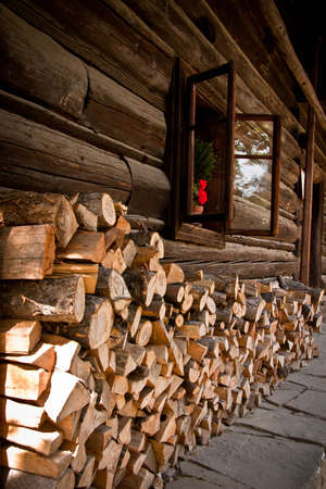 Woodpile of chopped firewood in front of a wooden houseの写真素材