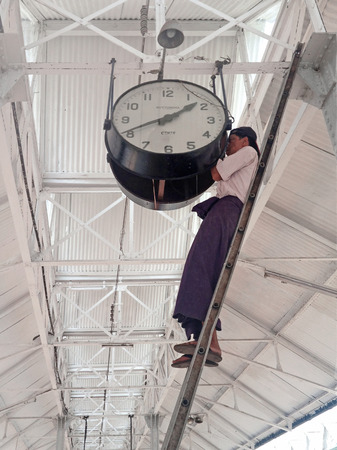 YANGON, MYANMAR - APRIL 17, 2013 :Burmese Man setting time on a big clock in (Rangoon) Yangon,...