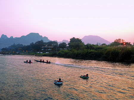 Recreation.Tourist kakaking and tubing along the river Nam Song at sunrise. Vang Vieng, Laos.の写真素材