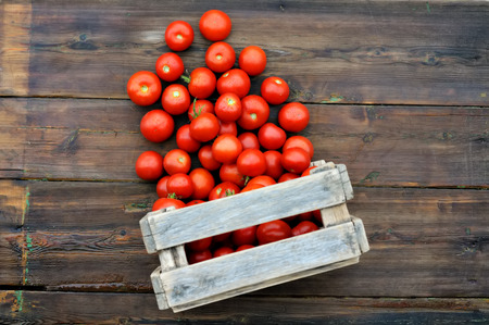 Tomatoes in a wooden box on a wooden table. Scattered tomatoes.の写真素材