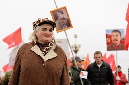 Orel, Russia, November 7, 2017: October Revolution anniversary meeting. Senior lady in bright makeup with Stalin portraits on backgroundのeditorial素材
