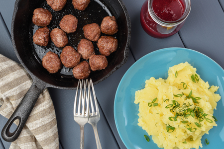Sweden meatballs fried in rustic cast iron pan served with mashed potatoes with leek and berry sauce on wooden gray table above viewの写真素材