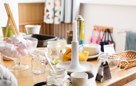 Marshmellow in glass vase, candle, grater and miscellanious kitchen utencils on wooden table horizontalの写真素材
