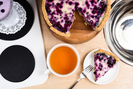 Homemade tasty blueberry pie and tea on toy kitchen with stove and sink above viewの写真素材