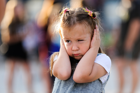 Orel, Russia, August 05, 2017: City Day. Little girl shuts her ears not to hear noise with people...