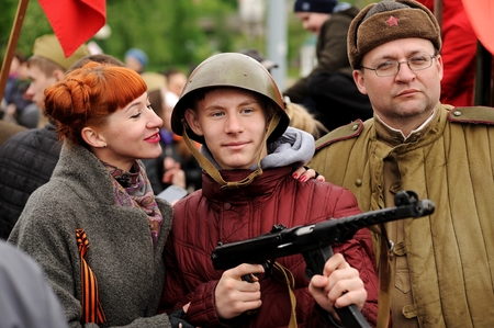 Orel, Russia - May 9, 2017: Victory Day selebration. Red haired girl and young man in Soviet war helmet with rifle taking photoのeditorial素材
