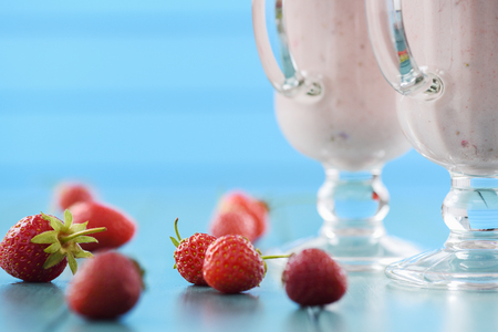 Strawberry milk cocktail in Irish mugs and fresh strawberries on light blue table closeup with copyspaceの写真素材