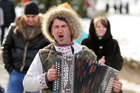 Orel, Russia - February 26, 2017: Maslenitsa fest. Man in fur hat playing bayan closeupのeditorial素材