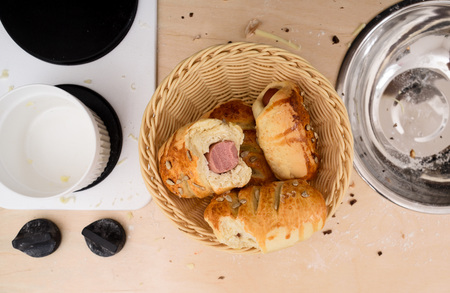 Basket with sausage rolls on toy kitchen next to stove and sink overhead view