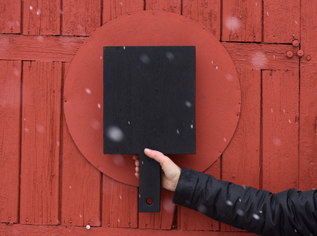 Black cutting board held in hand on red textured wooden background copyspaceの写真素材