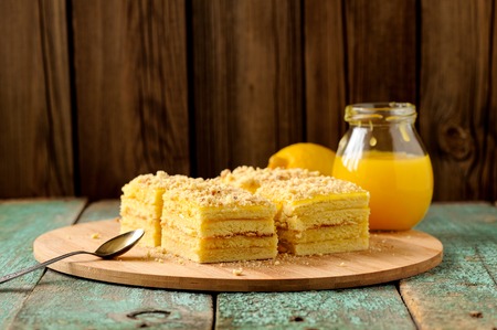 Homemade yummy layered lemon cake served with tea and lemon curd on bamboo plate with copyspace