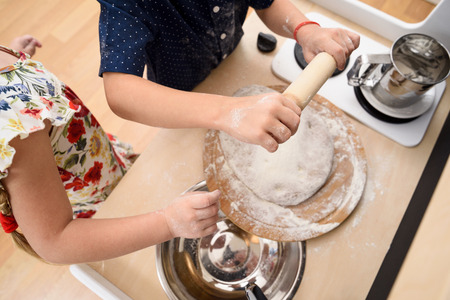 Home cooking. Children rolling dough for cookies in toy kitchen closeup