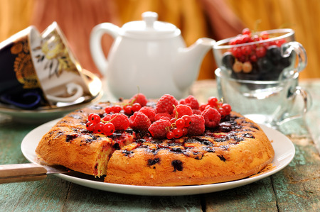Homemade upside down berry cake served with fresh currants and raspberries cutted closeup