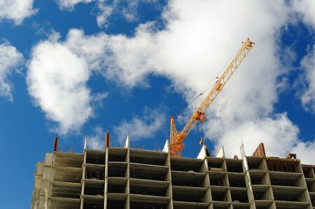 Carcass of new building and crane on blue cloudy sky copyspace horizontal