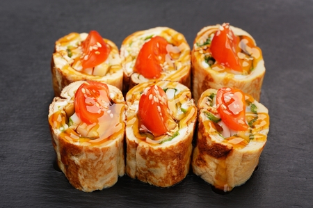 Fusion rolls with omelette and tomatoes on black palte closeupの写真素材