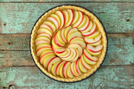 Raw homemade apple tart with two rows of apple slices top view
