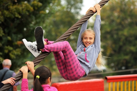 Orel, Russia, September 5, 2015: Smiling girl climbing steel rope closeupのeditorial素材