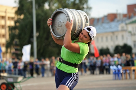 Orel, Russia, September 5, 2015: Woman carrying heavy metal keg in competition closeupのeditorial素材