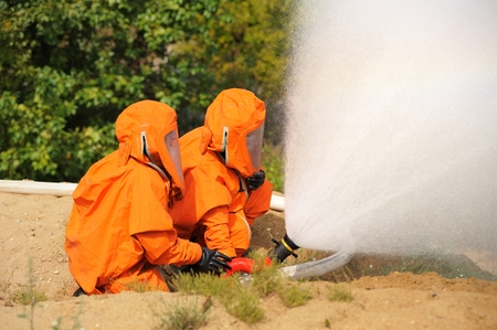Orel, Russia - August 28, 2015: Two Russian Emergency Control firemen in orange uniform extinguishing fire by fire-hose closeupのeditorial素材